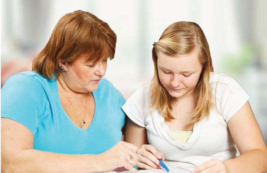 Adult helping a young person with something in a workbook. Appears to be school work.