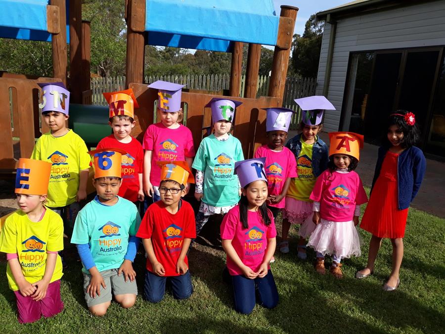 A group of children wearing HIPPY t-shirts and hats with letters and numbers on them.HIPPY