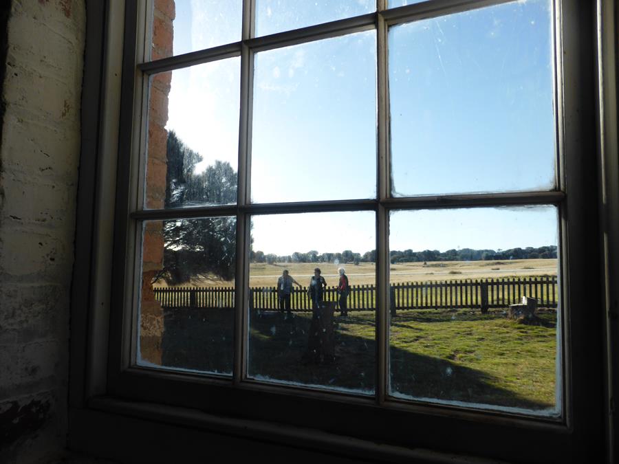 Photo looking out of a window where some aboriginal elders are standing and looking at the house and the gardens