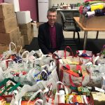 CEO Chris Jones is sitting amongst a floor covered in bags of gifts donated for the Christmas Appeal.