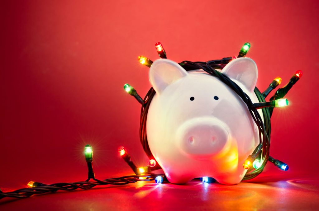 Cute piggy bank decorated with christmas lights to indicate saving money at Christmas