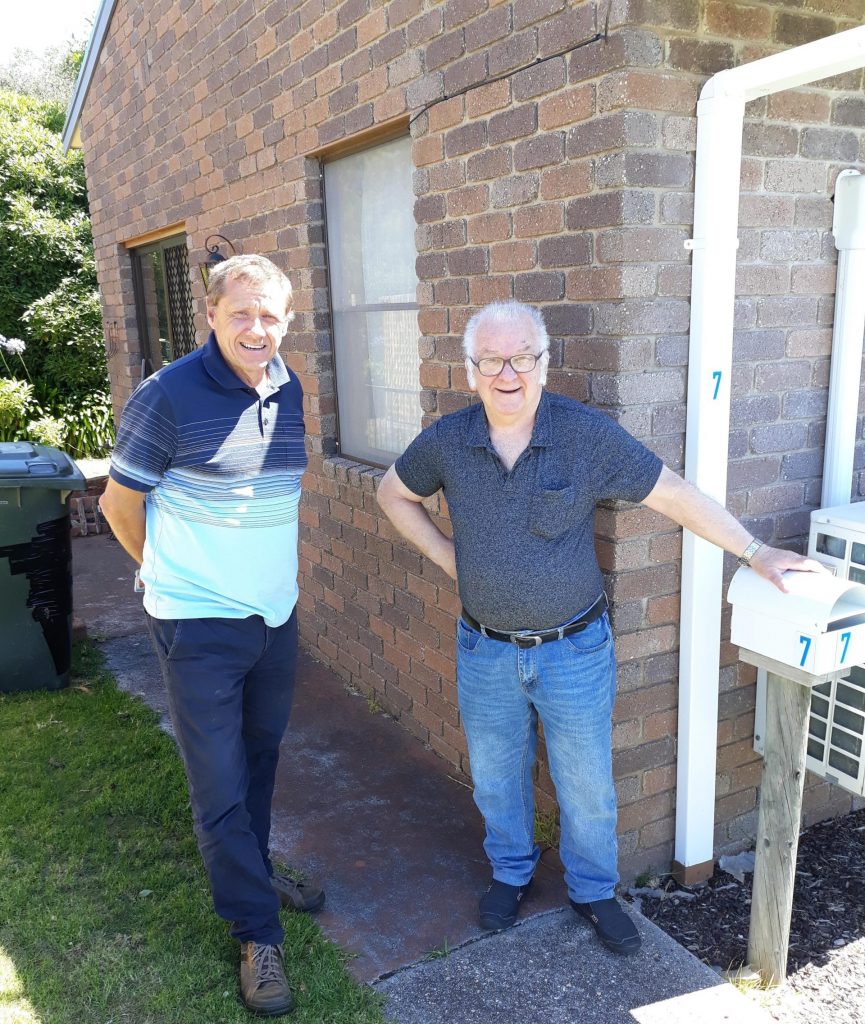 two men standing beside a house