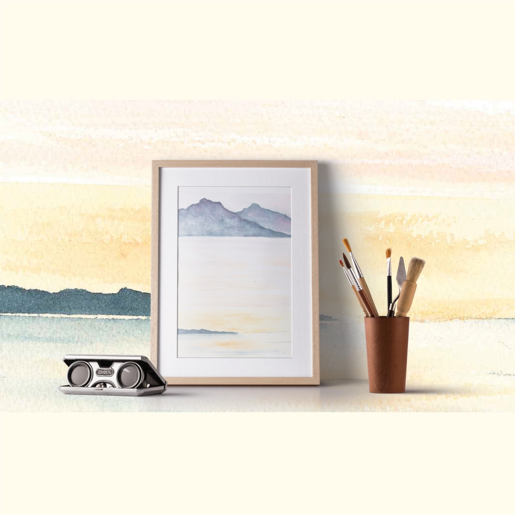 photo of a framed watercolour painting of tasmanian west coast wilderness, a cup with a collection of paintbrushes in it and a pair of binoculars