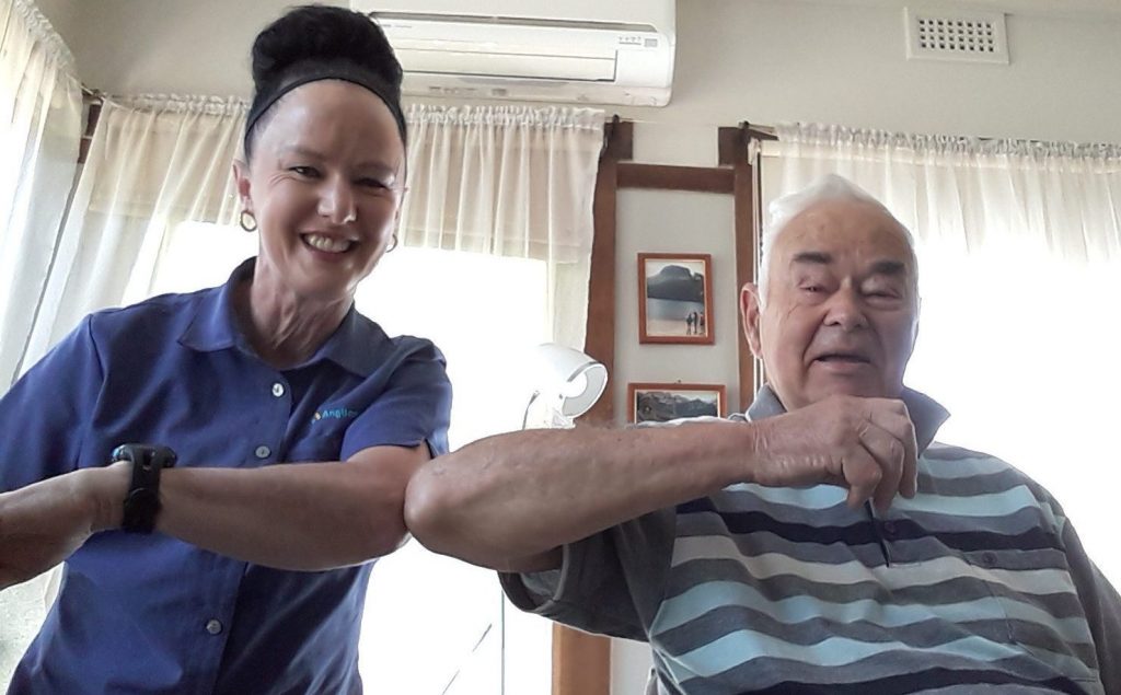 Photo of Anglicare Home Care team member Wendy touching elbows with client David. Big smiles on their faces.