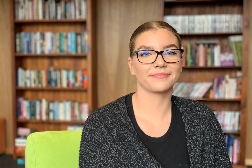 Photo of Ruby a young person sitting in a library.