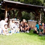 Children and mothers sitting out on the grass