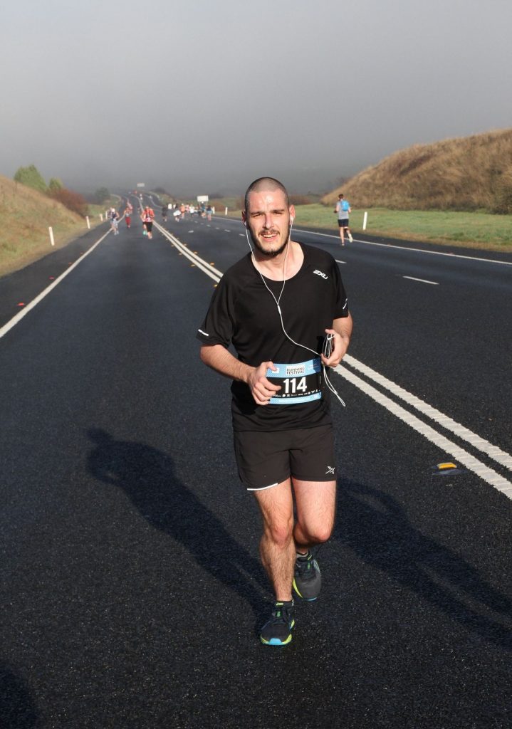 Eben is running along a road competing in a half marathon. He is listening on his headphones as he runs.