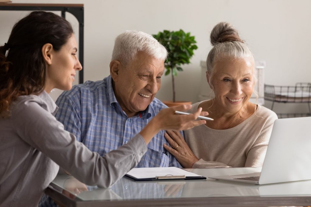 A couple sitting with someone looking at a computer screen. They are smiling.