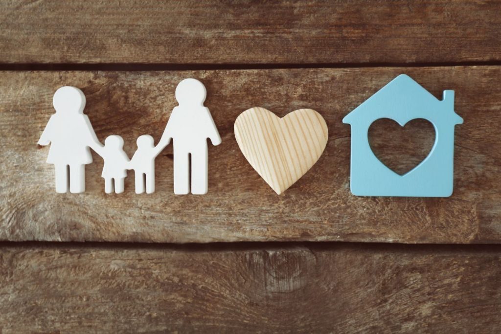 An image showing a timber cut out design of family, a heart and a house.