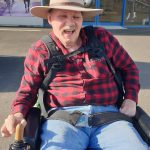 Gary is sitting in his wheelchair outside. He is wearing a new Akubra country western style felt hat.