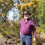 Kees is standing in a garden with lots of trees.