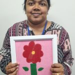 A lady holding her artwork of a flower.