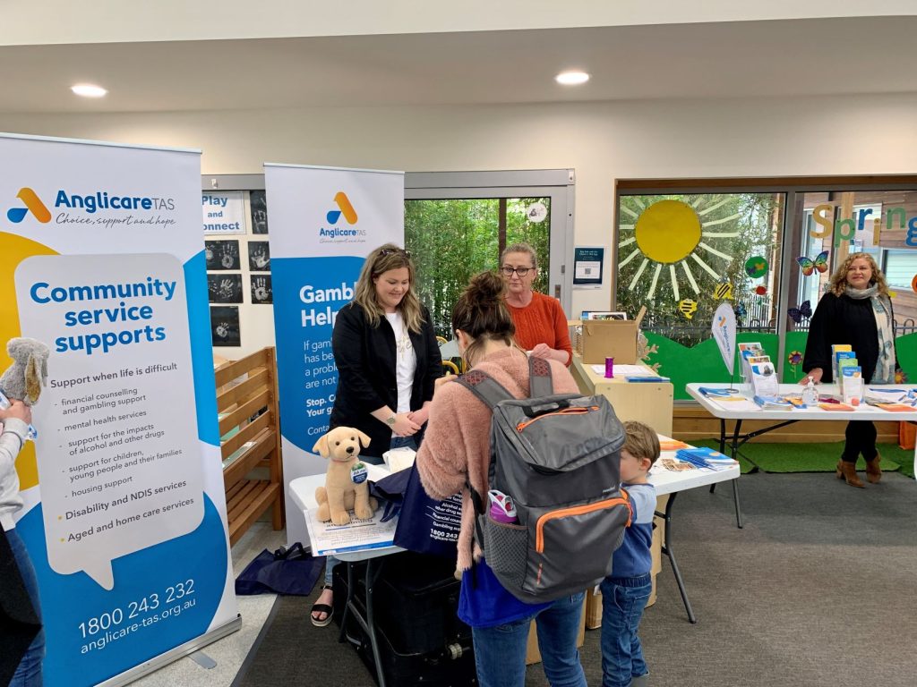Anglicare Community Services staff members at the Devonport Child and Family Centre speaking to visitors at a table display on support services.