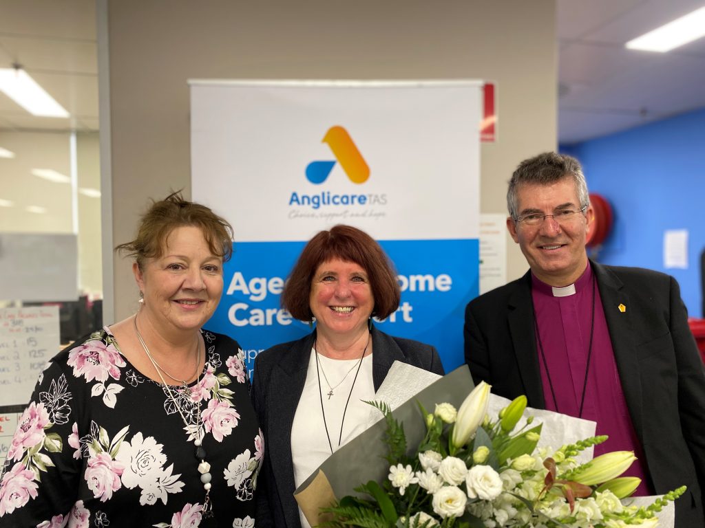 Connie holding flowers to farewell her from the Home Care Team. She stands with Sharon Scarlett and Chris Jones.