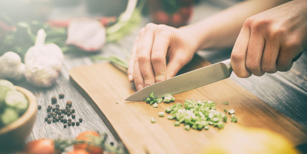 A person is cutting vegetables in a commercial kitchen.