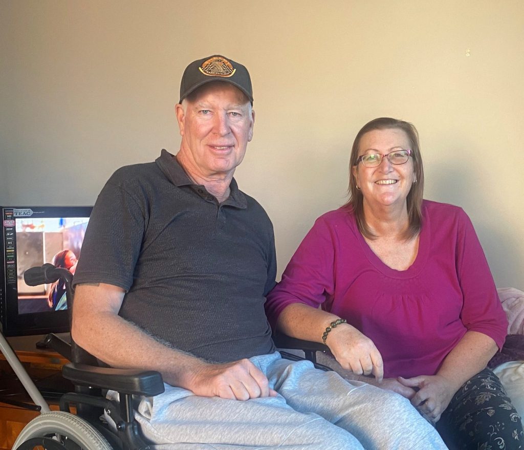 Photo of Kevin and Debbie sitting down beside each other smiling and looking happy.