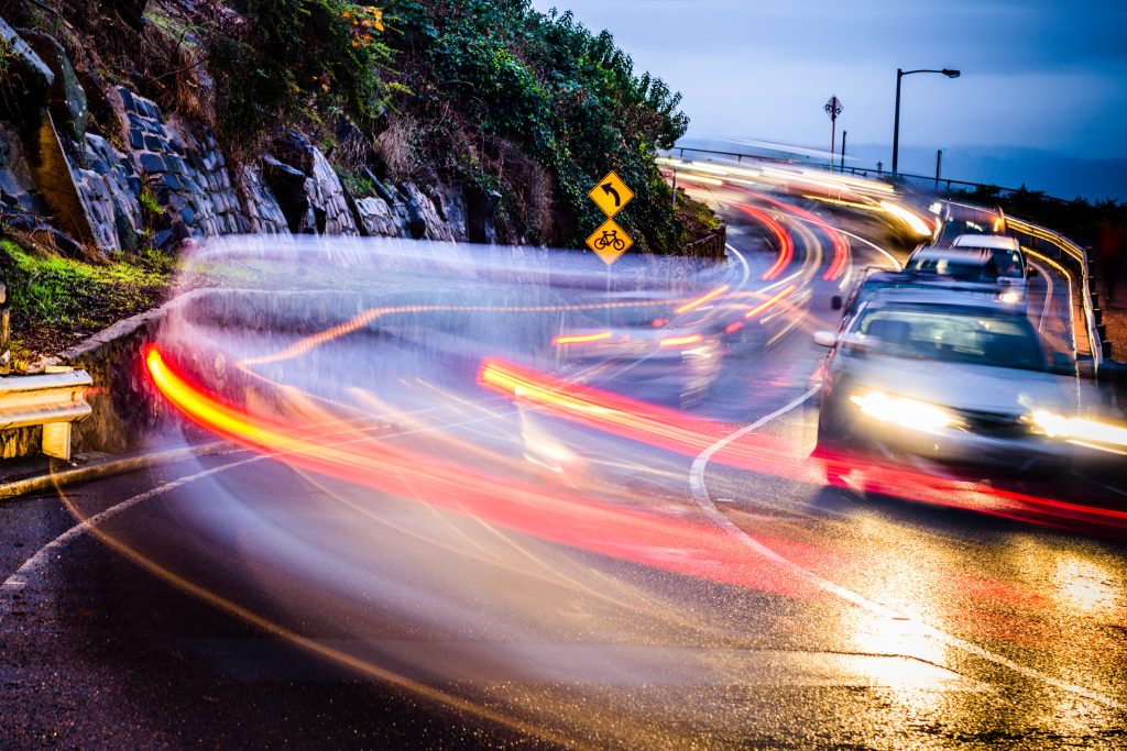 Cars driving with their car lights on at night in the rain.