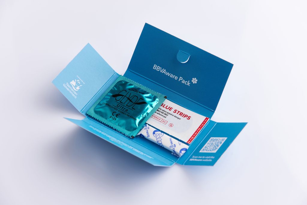 Photo of one of a small blue pack that has a condom, stick of chewing gum and a Band-Aid inside it.