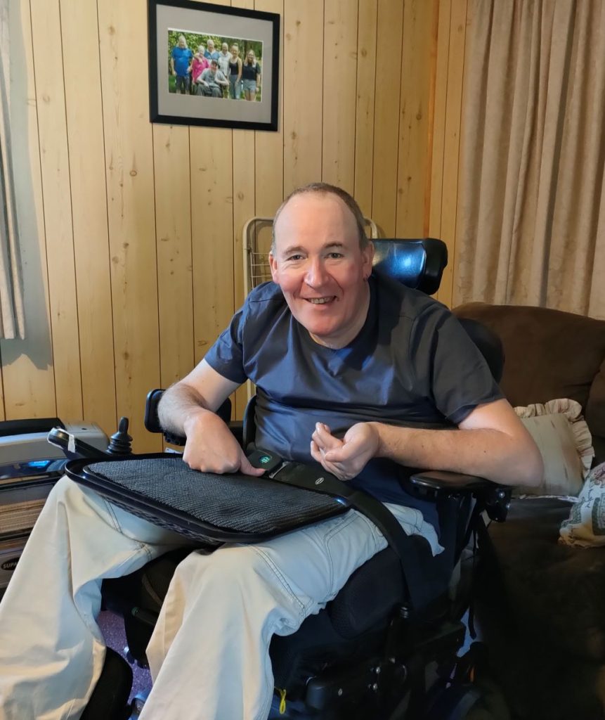 Photo of Dave sitting in his wheelchair looking happy.