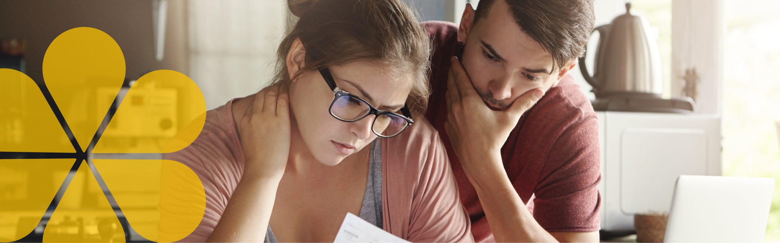 a couple sitting beside each other looking at pieces of paper looking concerned