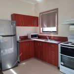 A kitchen within one of the units which has cupboards, sink, microwave, stove and oven and a large fridge and freezer.