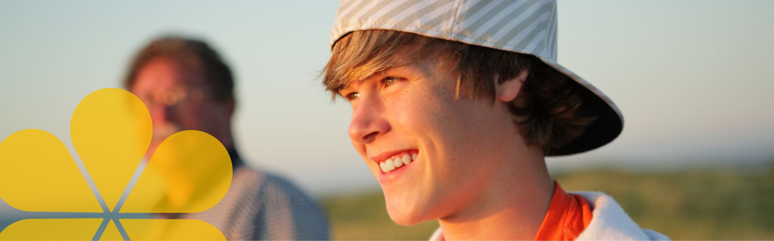young person wearing a baseball cap backwards and is smiling