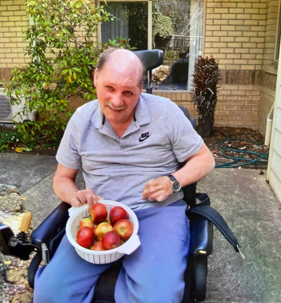 Client Garry is holding a bowl of fresh apples which he has just picked from his backyard orchard.