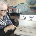 Lee is sitting at her desk looking at the original illustrations that she drew for her children's book.