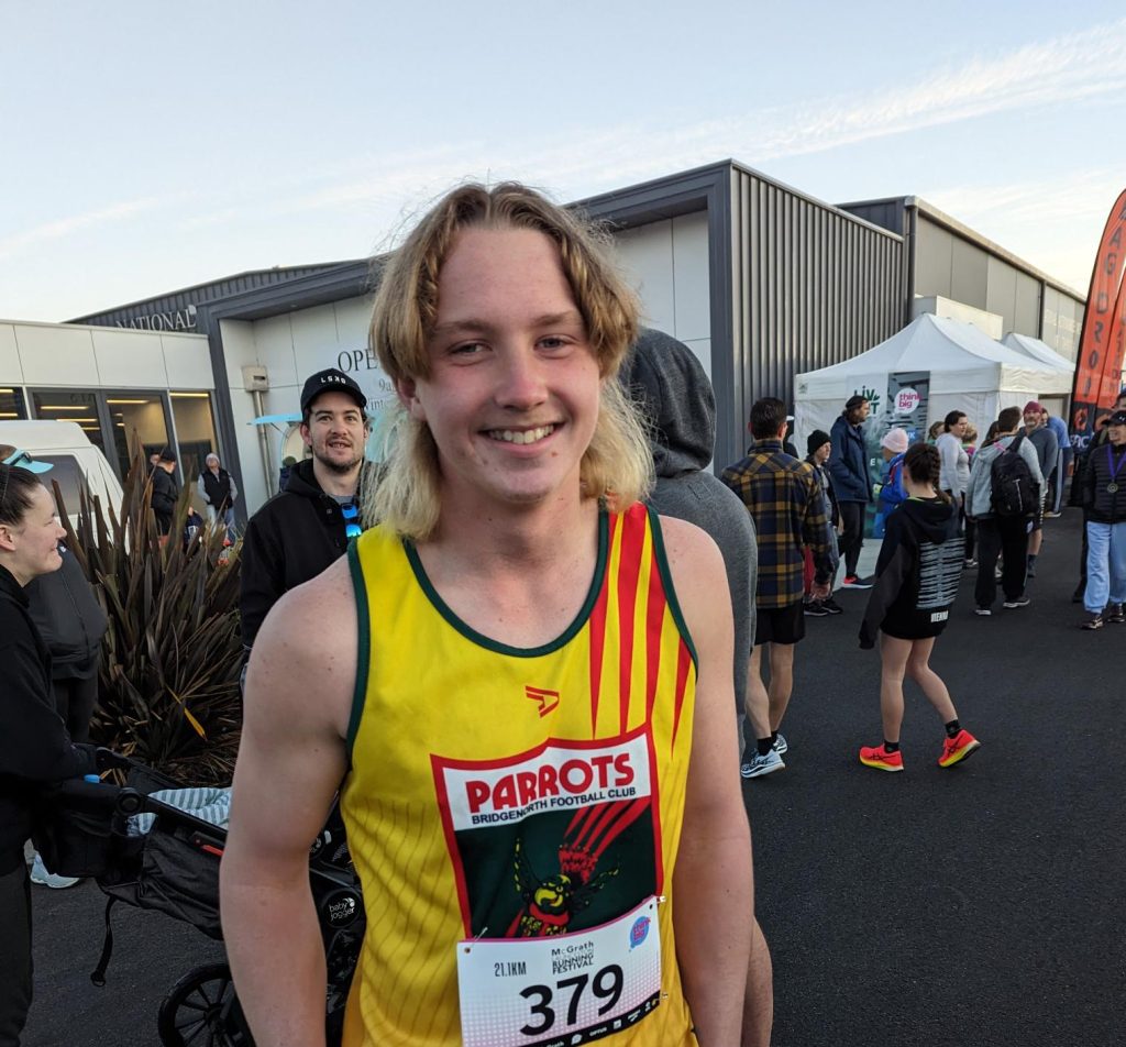 A photo of Ryleigh wearing his football club top just finishing the park run on a saturday. He is milling.