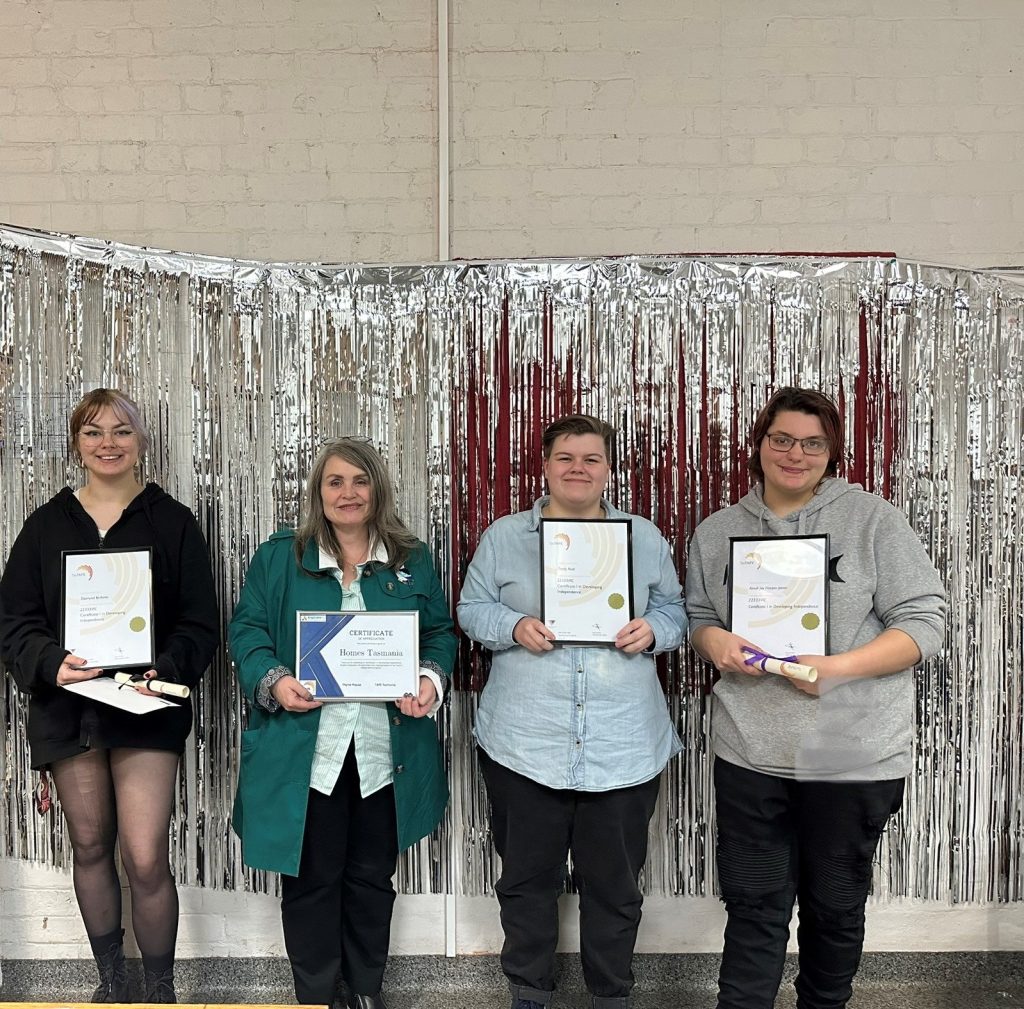 3 smiling young people from Thyne House standing with Justine Brooks from Home Tasmania who has just given each of them their TAFE course certificate and a voucher.