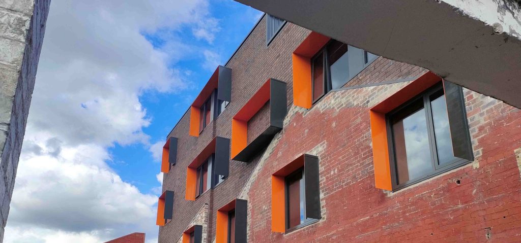 An image of Thyne House a Youth2Independence facility. It shows a red brick multistory building with rows of windows.