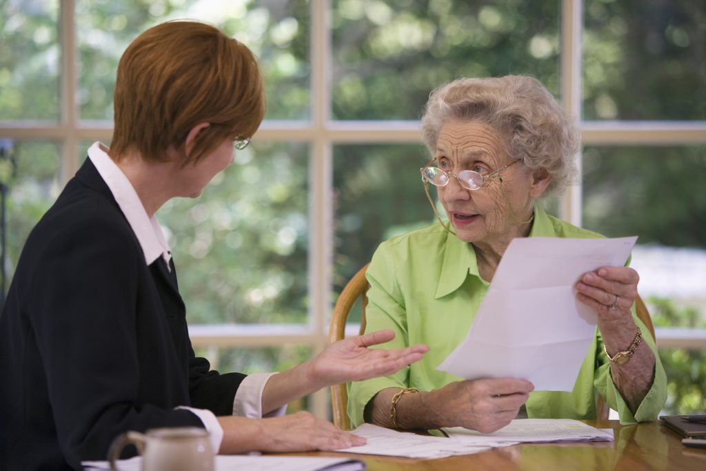 Two people sitting at a kitchen table. One person appears to be giving advice to the other.