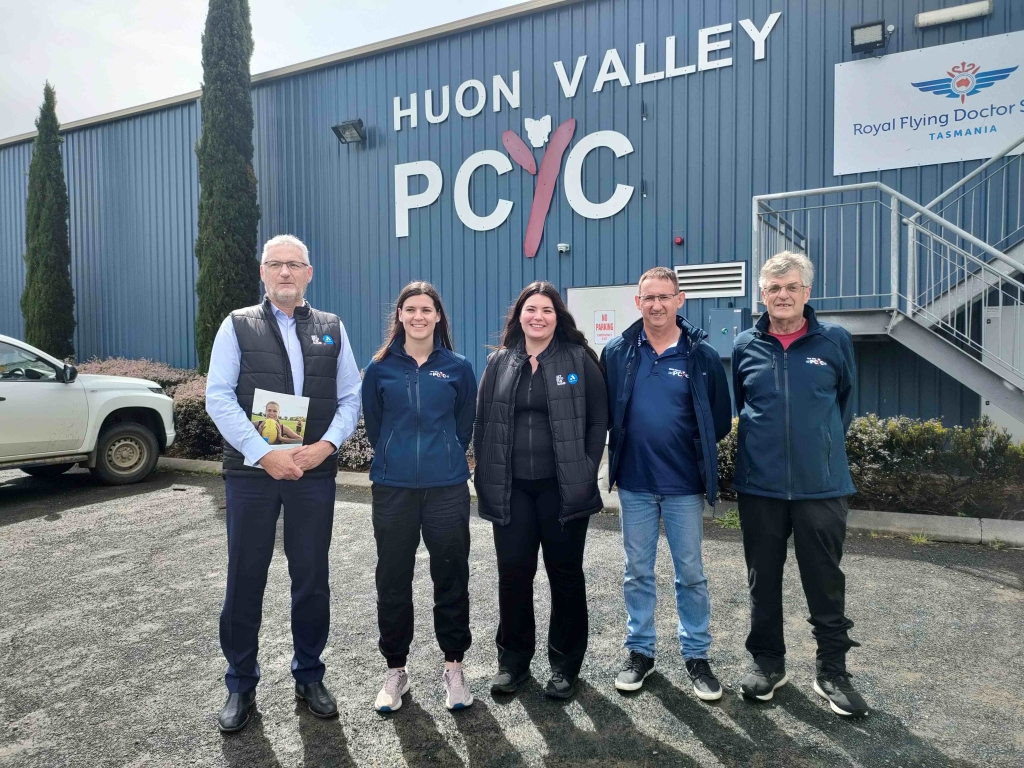 A group of people standing in front of the Huon Valley PCYC building in Huonville. They are representatives from both Anglicare Tasmania and the PCYC.