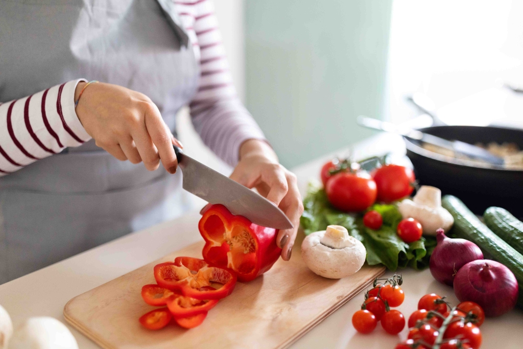 A woman is preparing vegetables for dinner. Access to good nutrition and adequate hydration is essential as we age.